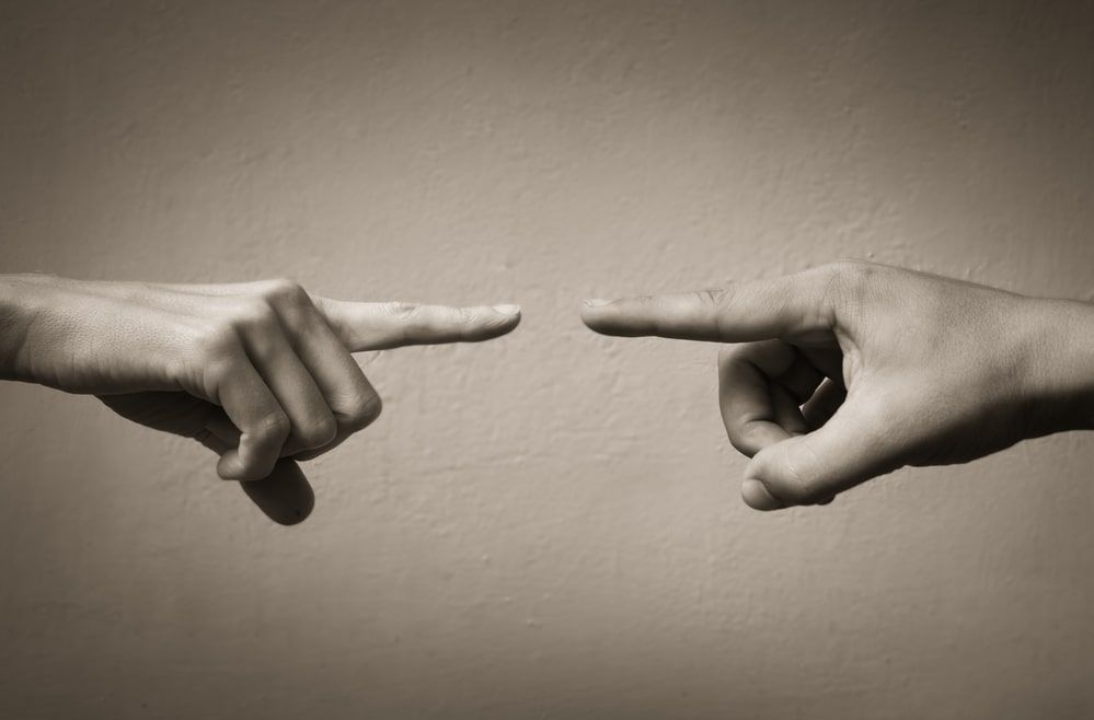 Two hands are pointing at each other with their fingers.