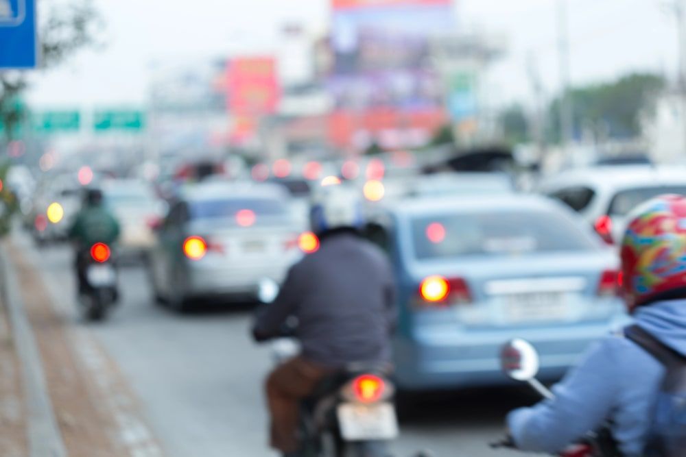 A blurry picture of people riding motorcycles on a busy street.