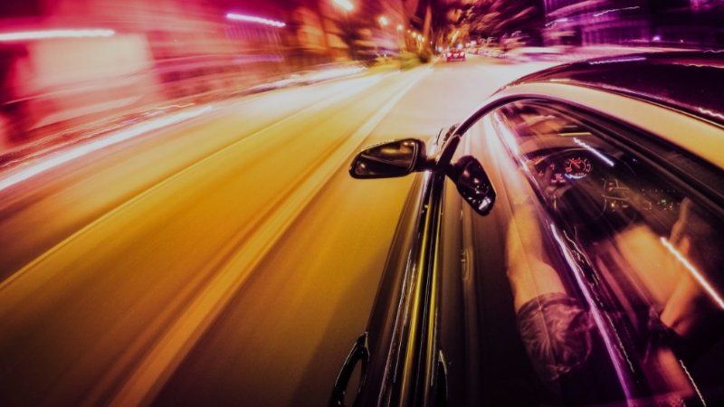 A car is driving down a highway at night.