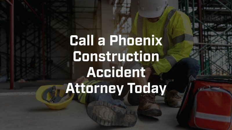 A construction worker is kneeling down next to a person who is laying on the ground.