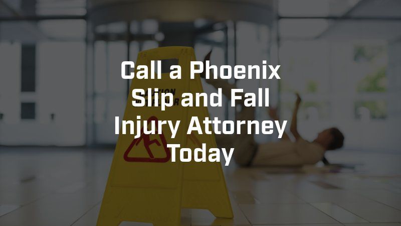 A man is laying on the floor next to a yellow caution sign that says call a phoenix slip and fall injury attorney today