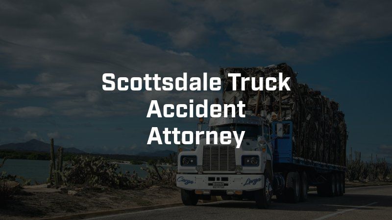 A truck is driving down a road next to a body of water.