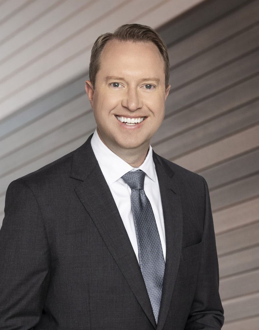 A man in a suit and tie is smiling for the camera