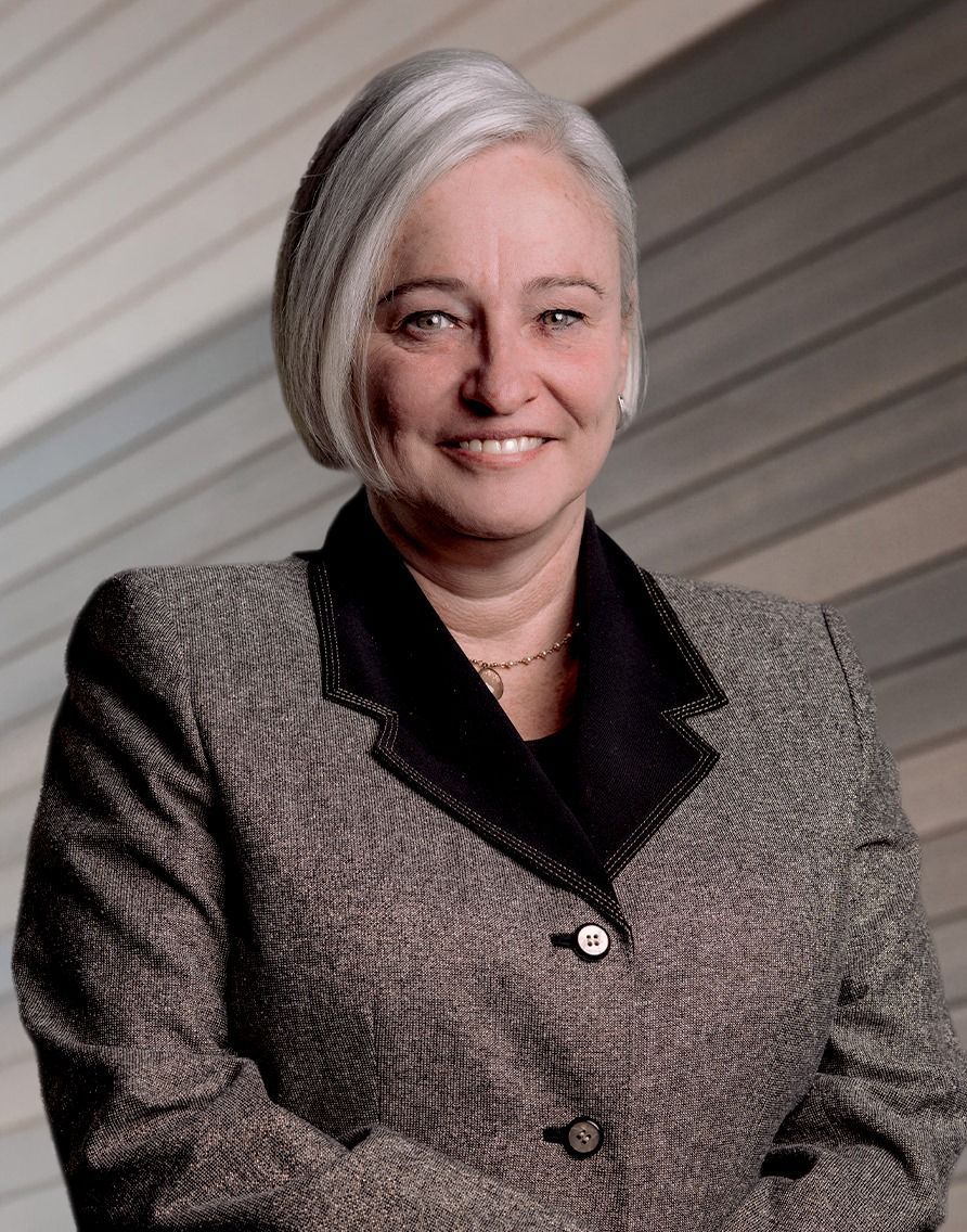 A woman in a suit is smiling with her arms crossed