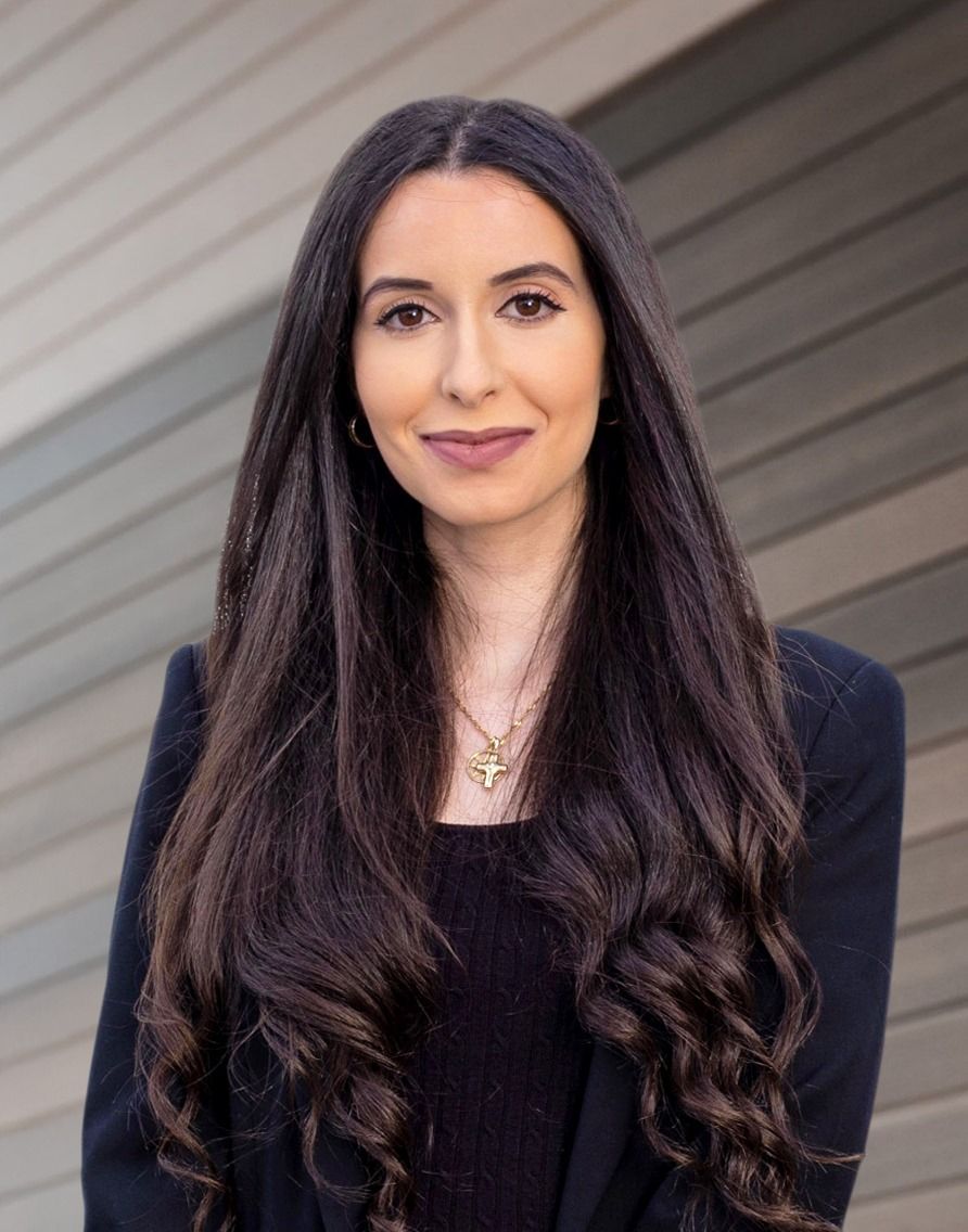 A woman with long hair is wearing a black jacket and a necklace.