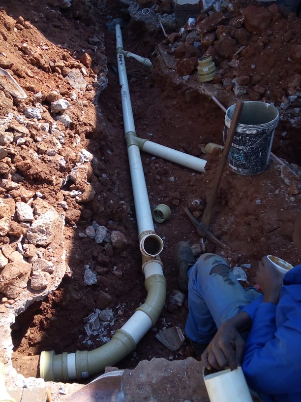 Plumbing sewage pipes being installed in a trench in the ground