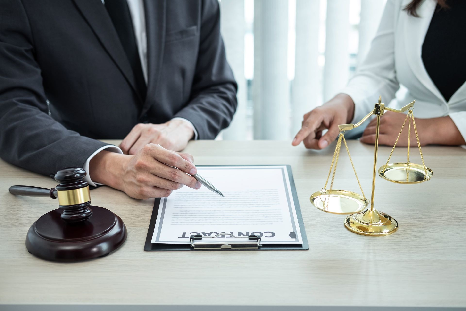Lawyers reviewing a document with a gavel and scales of justice on a desk