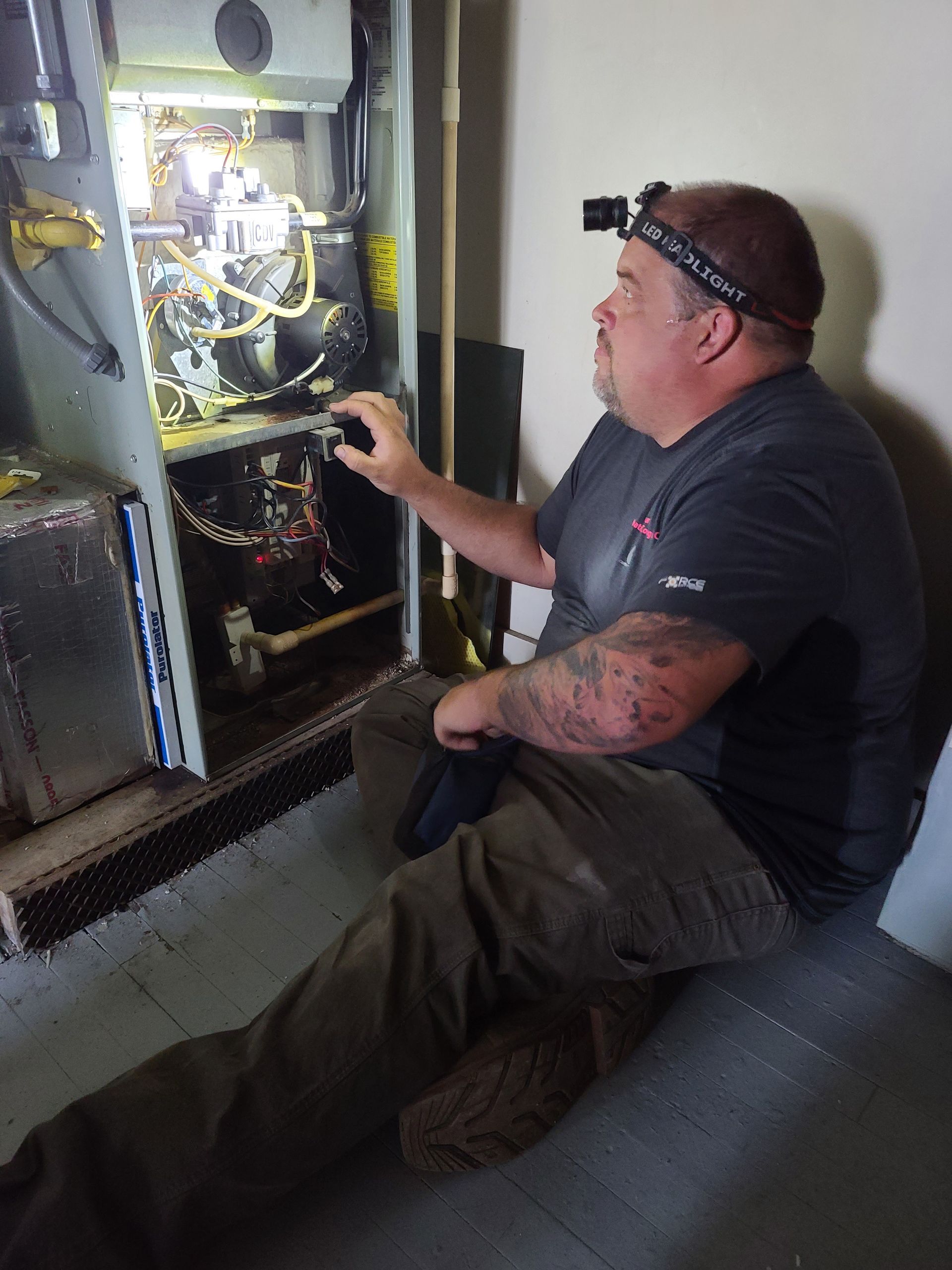 A man is sitting on the floor working on a heater.