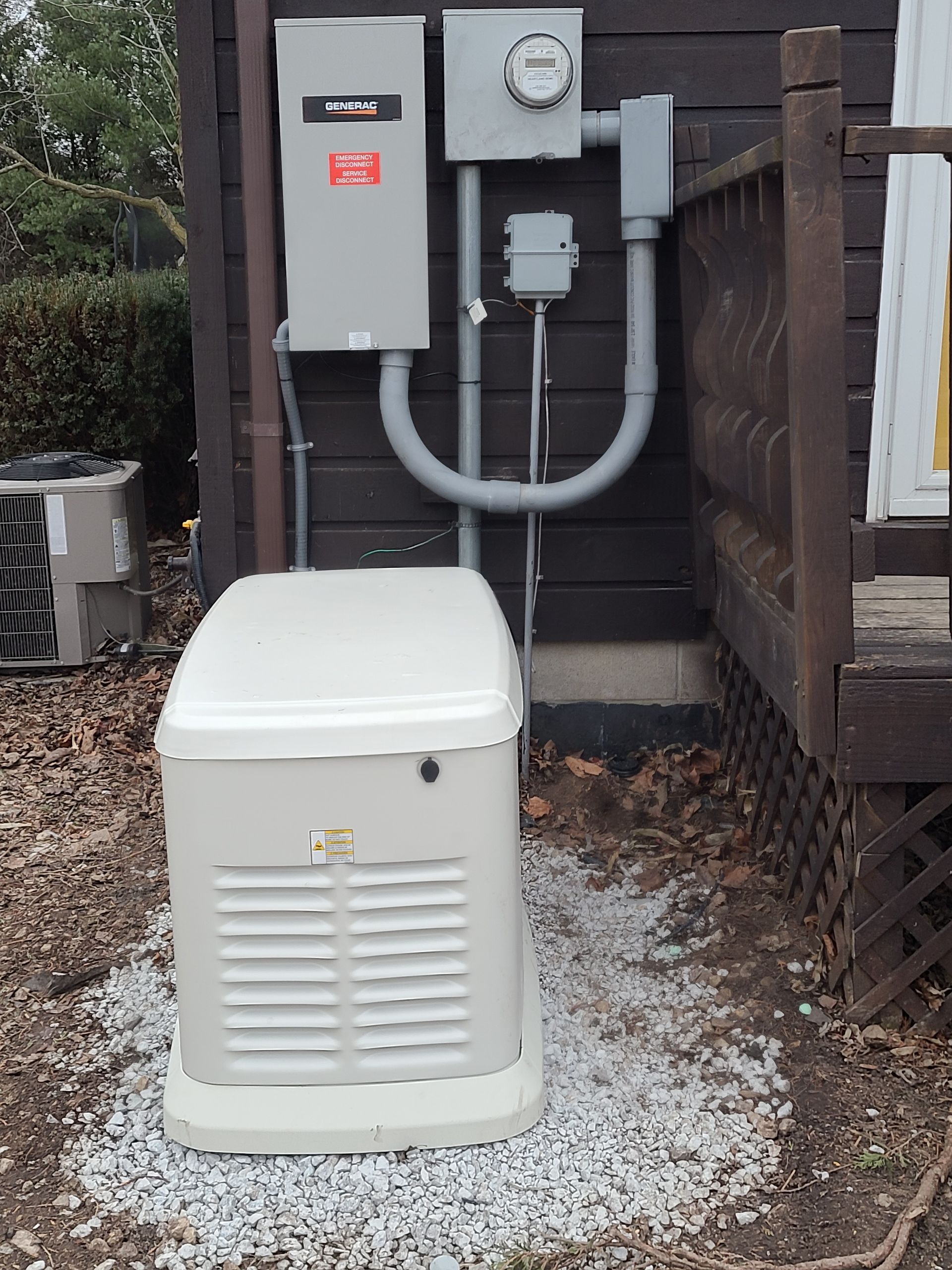 A white generator is sitting outside of a house