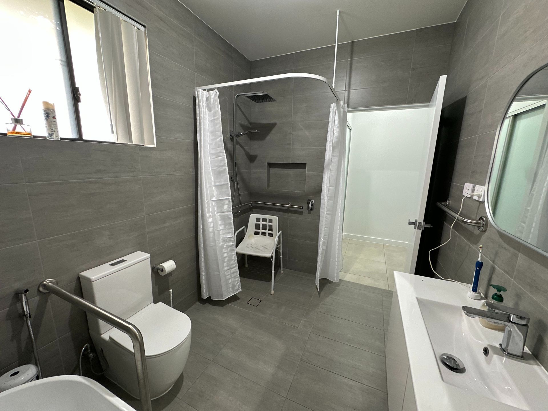 Accessible Bathroom With Gray Tile, Open Shower With Curtain — My Coast Projects in West Gosford, NSW
