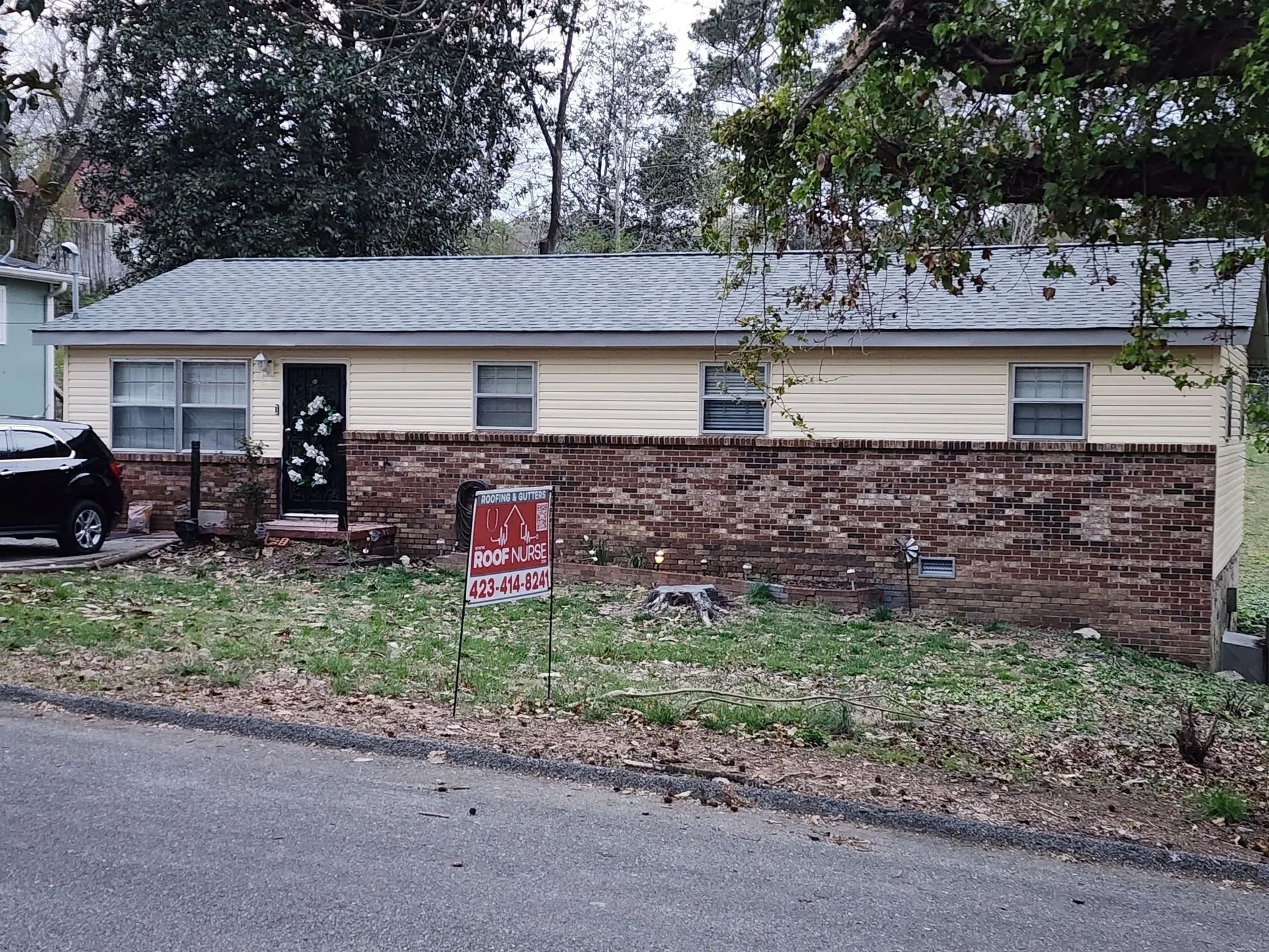 A single-story, light yellow house with a brick-covered lower exterior and a 