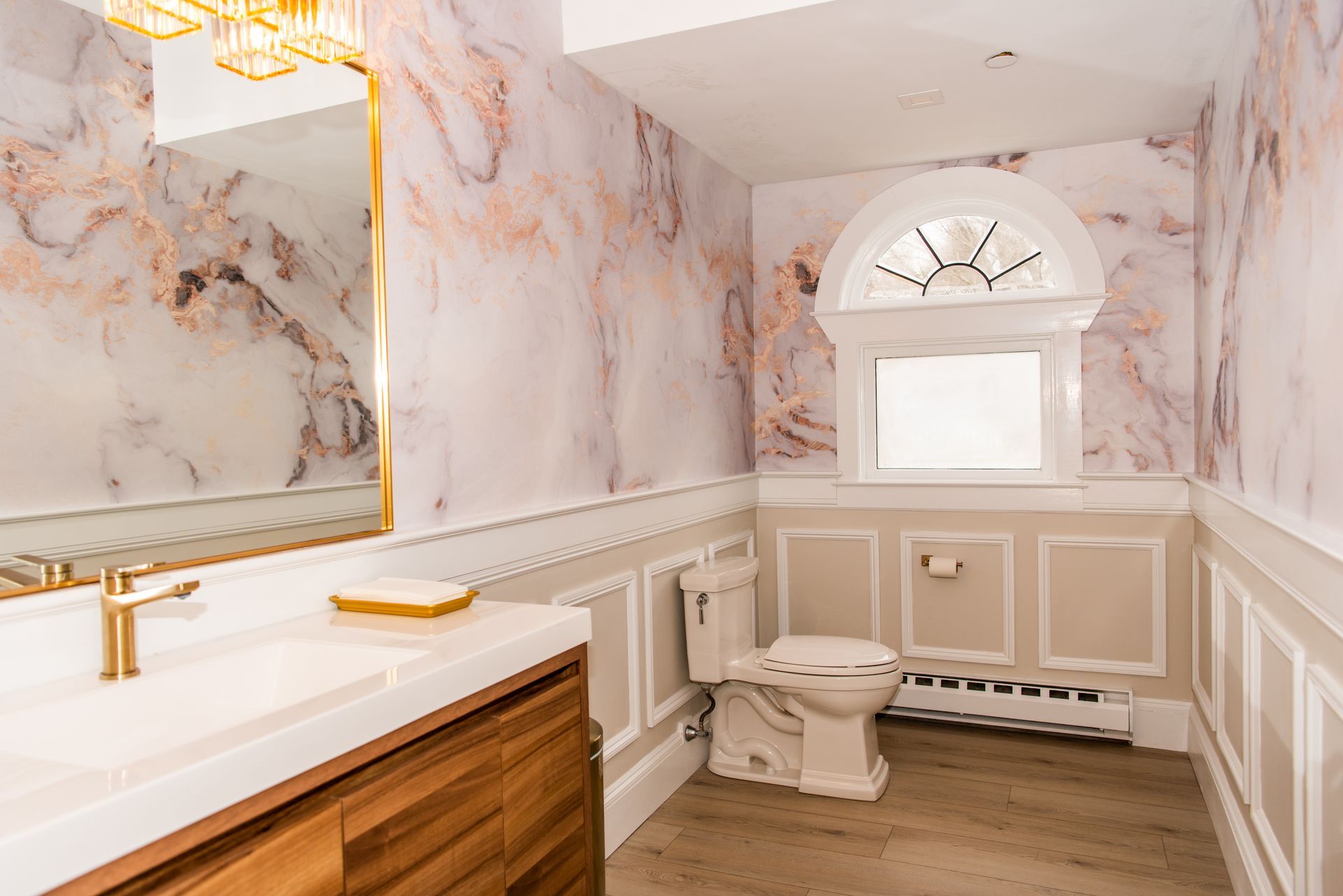 a bathroom with marble walls , a toilet , a sink and a mirror .