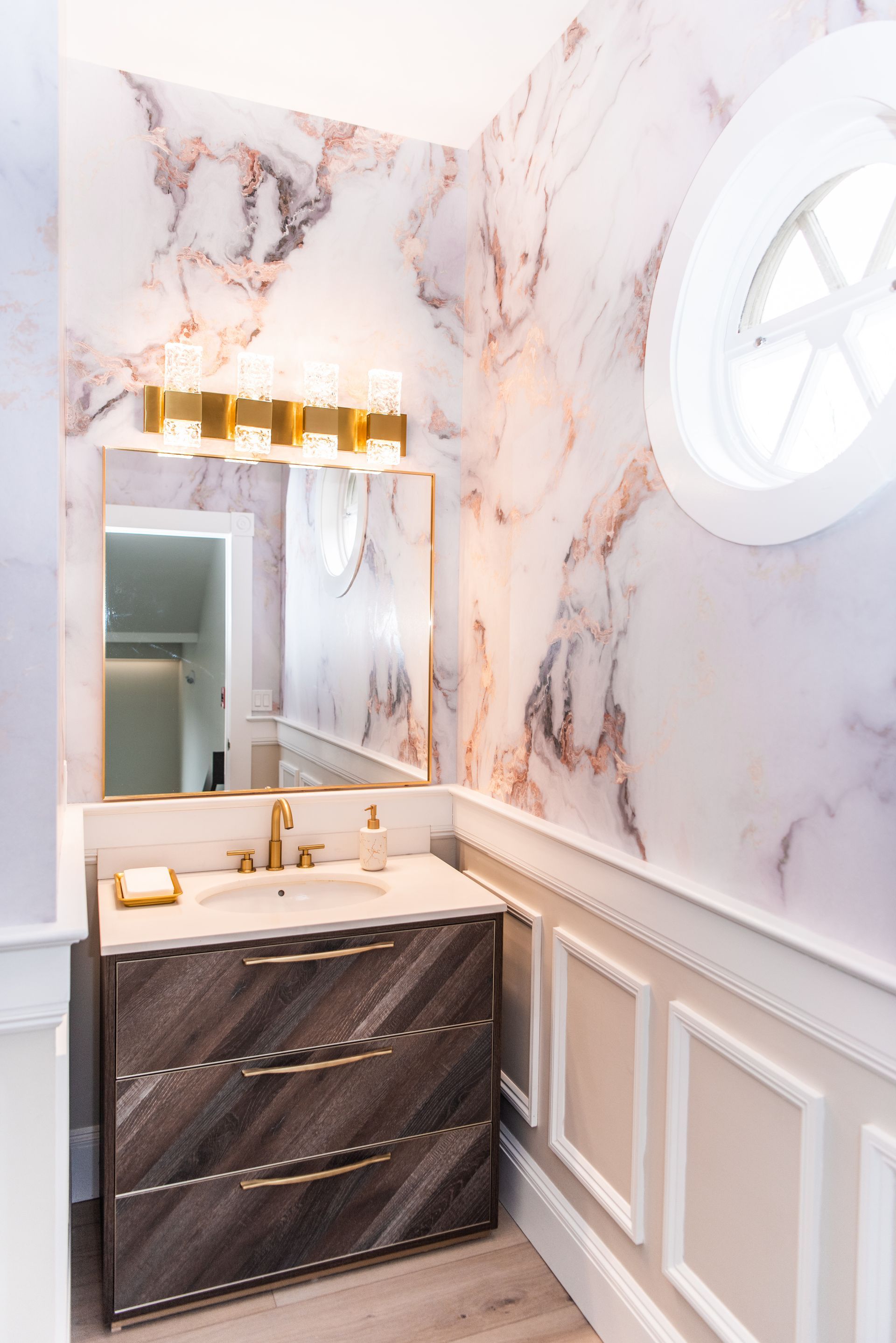 a bathroom with a sink , mirror and marble wall .