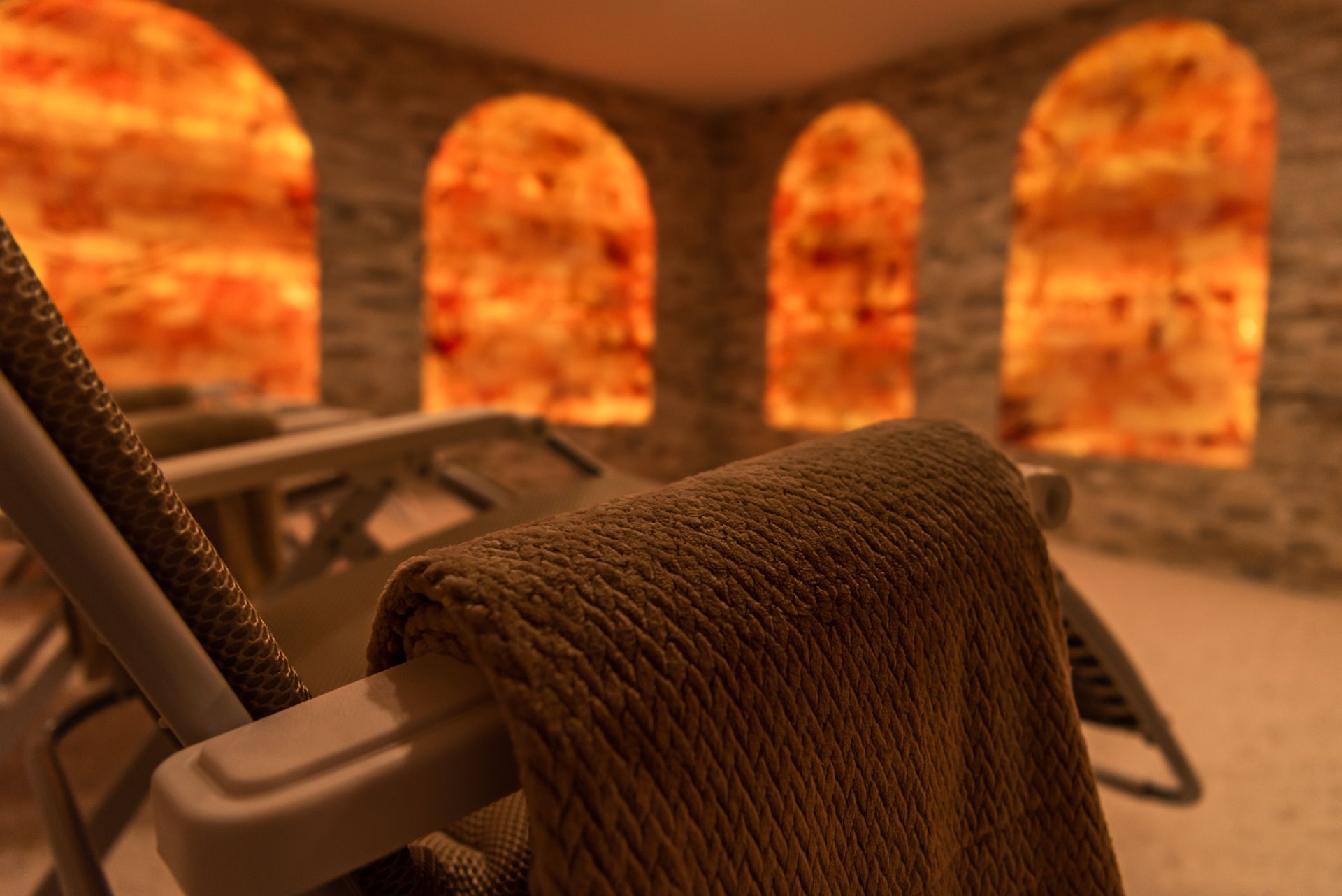 a chair with a blanket on it in a room with arched windows .