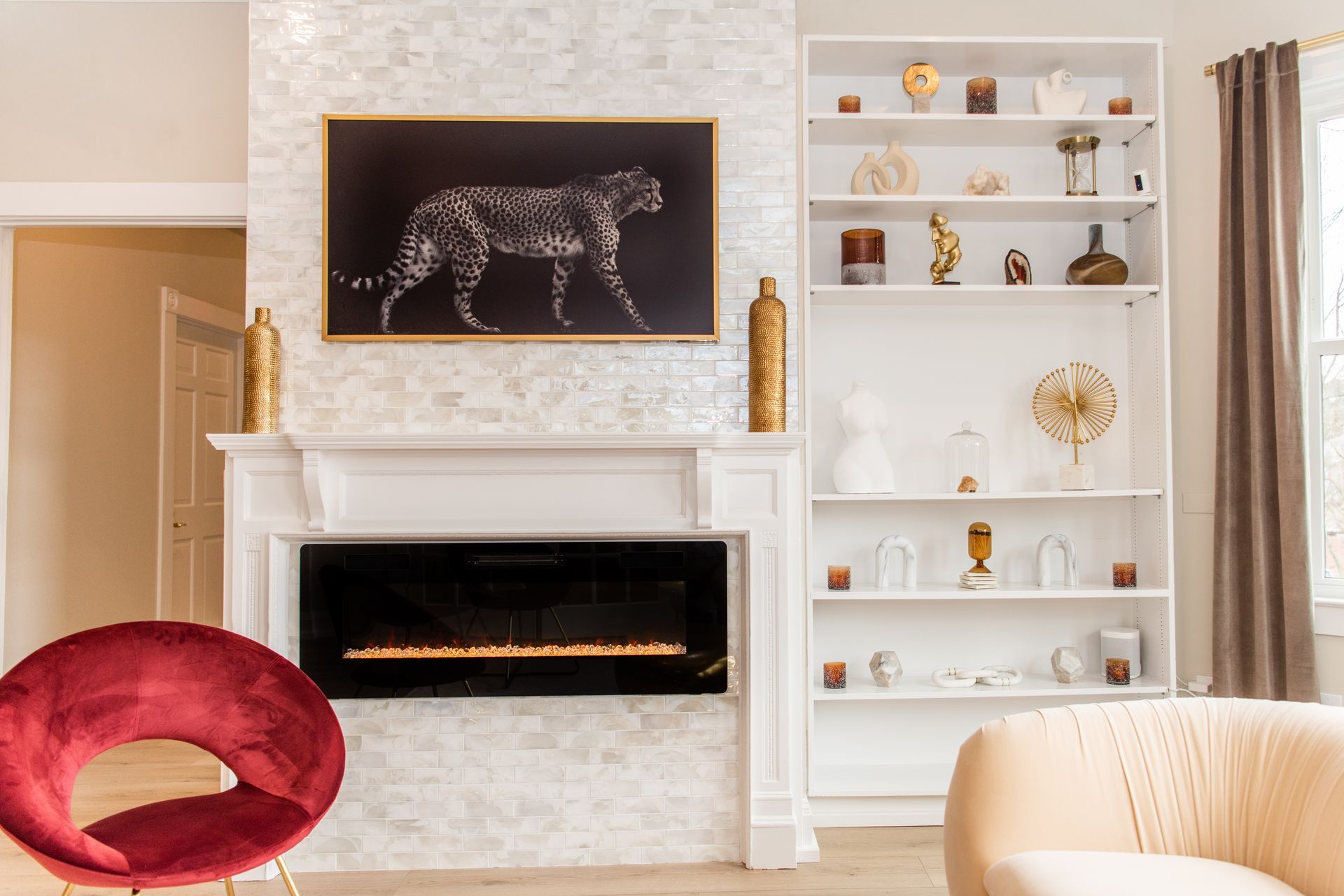 a living room with a fireplace , chairs , shelves and a painting of a cheetah on the wall .