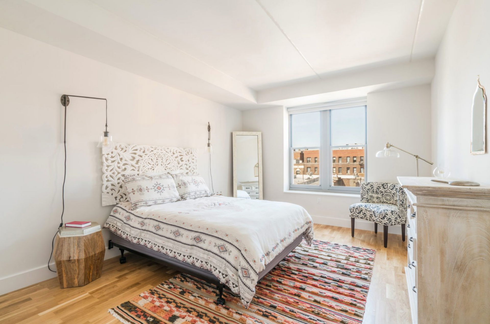 a bedroom with a bed , dresser , chair and rug .