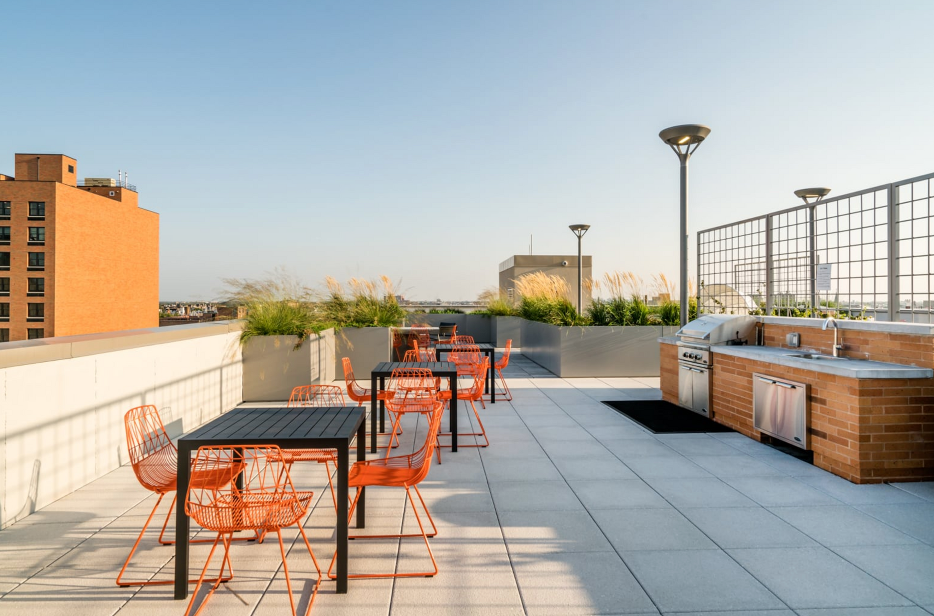 a rooftop patio with tables and chairs and a grill .