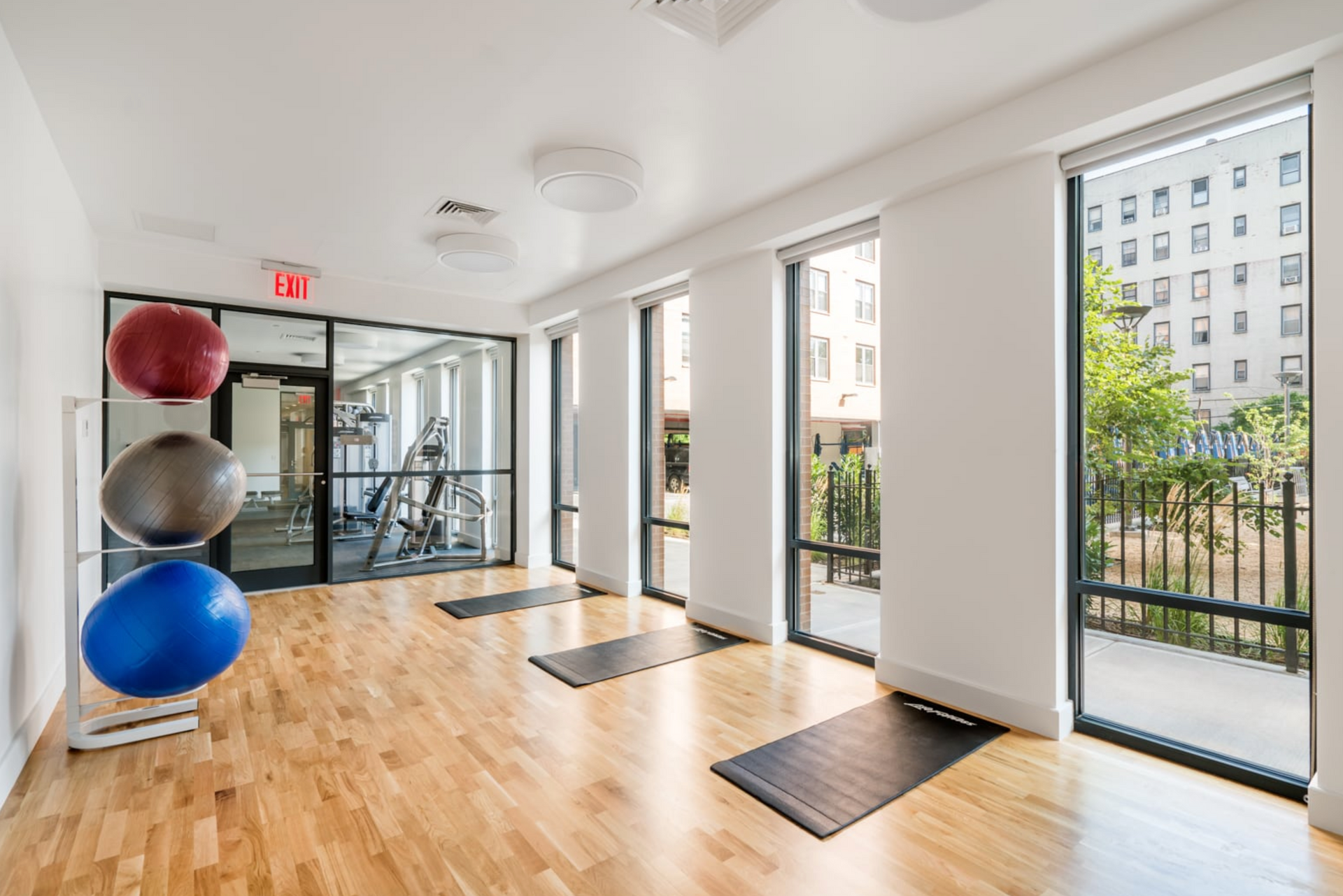 a large empty gym with a lot of windows and exercise balls .