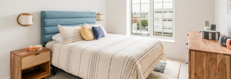 a bedroom with a bed , nightstand , dresser and window .