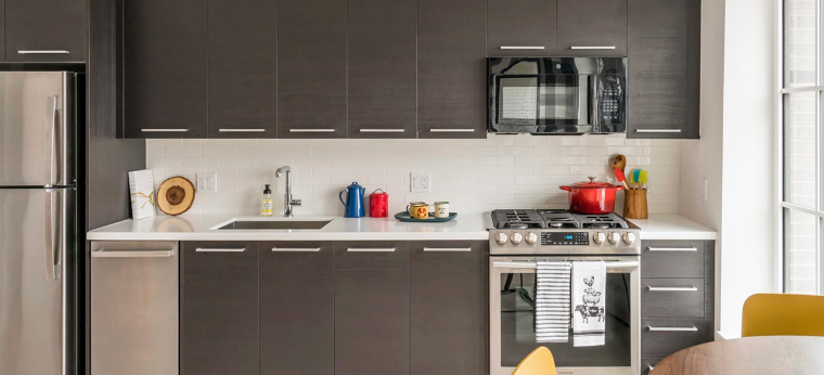 a kitchen with stainless steel appliances and gray cabinets .