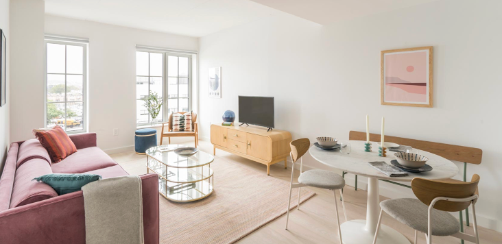 a living room with a pink couch , table and chairs .