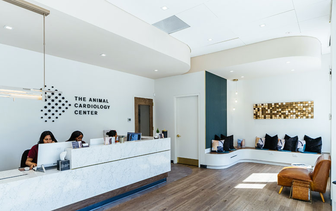 A woman is sitting at a desk in a hospital reception area.