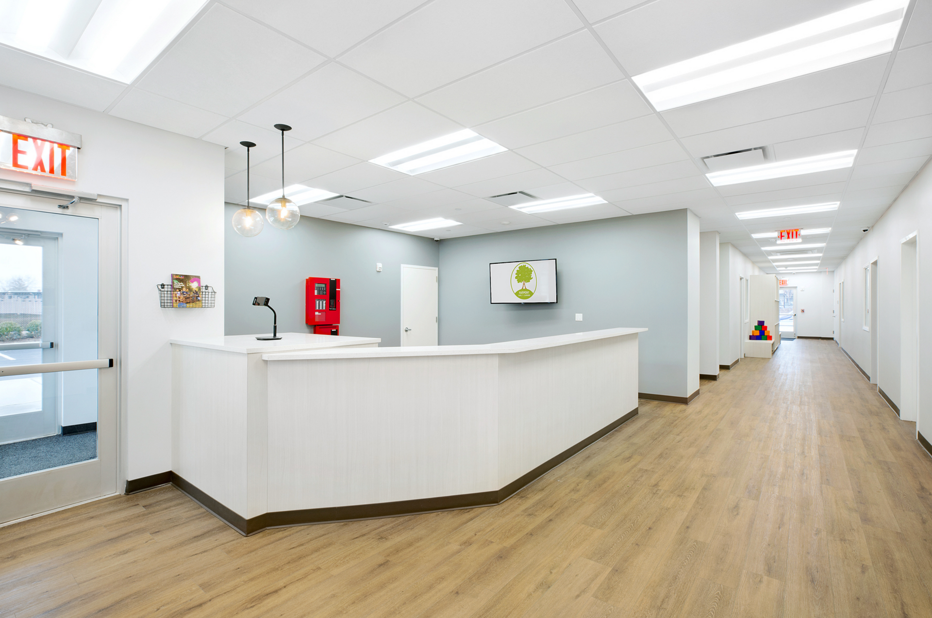 A hospital lobby with a white counter and a red exit sign.