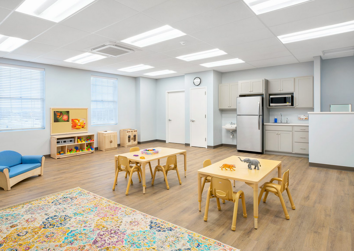 A classroom with tables and chairs and a refrigerator.