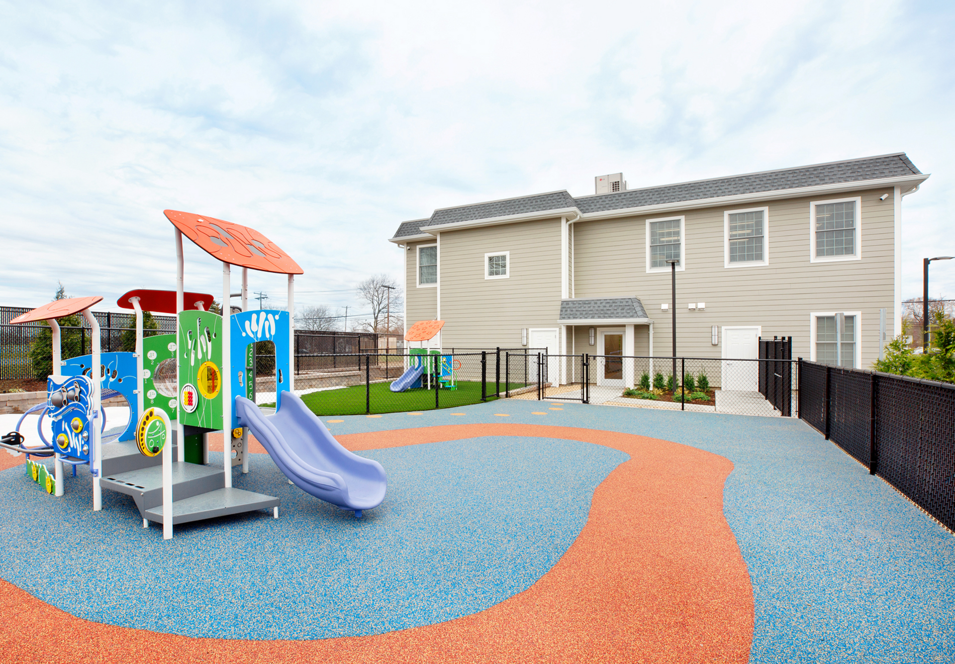 A playground with a slide and a house in the background