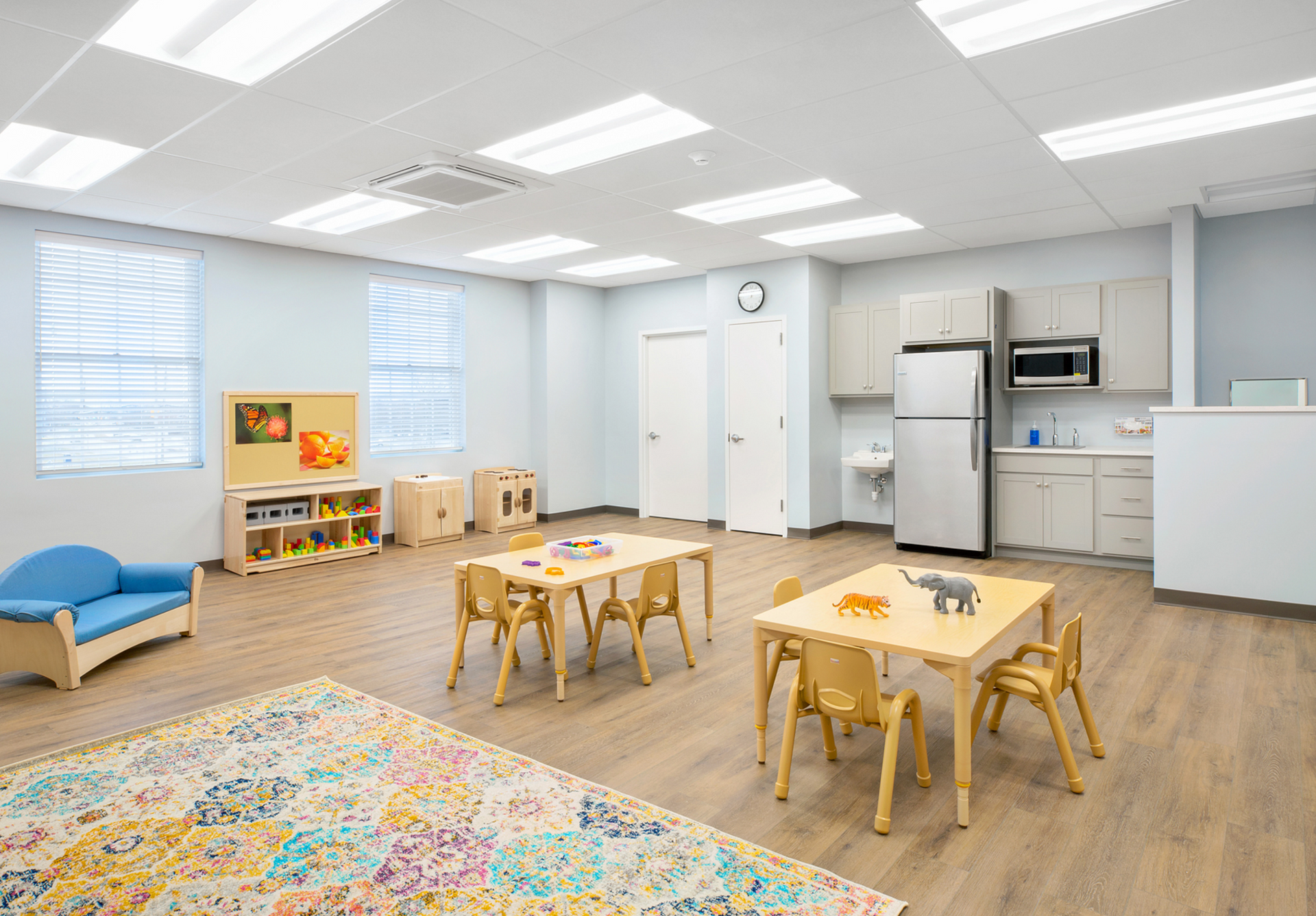 A classroom with tables and chairs and a refrigerator.