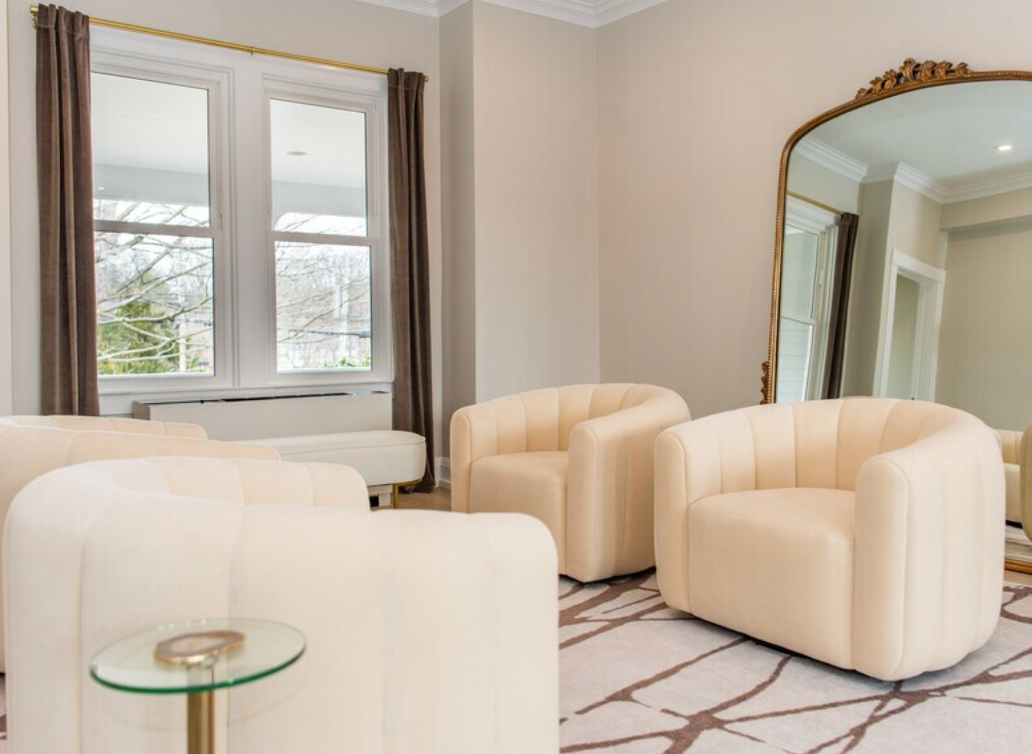 a living room with white chairs and a large mirror