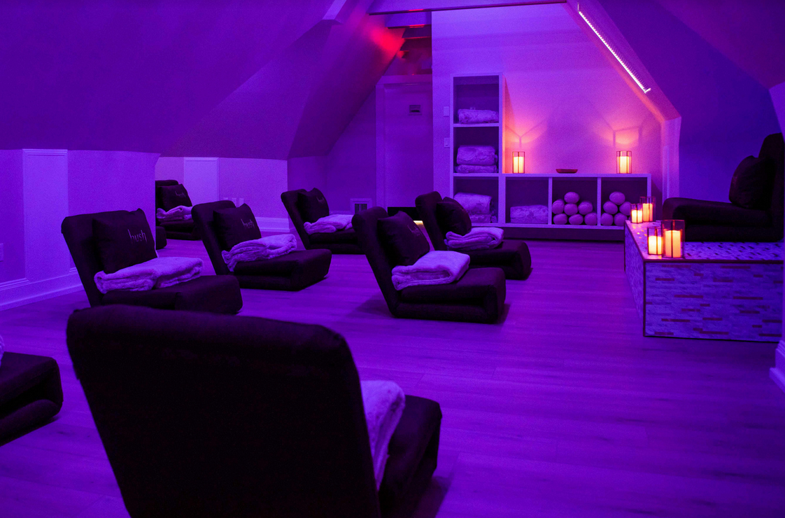 a room with purple lights and chairs and candles .