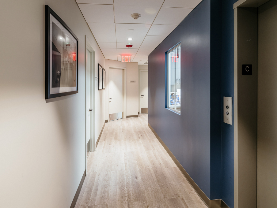 A long hallway with a picture on the wall and a window.