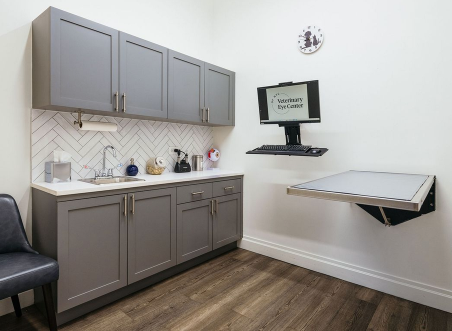 A kitchen with gray cabinets and a computer on the wall.