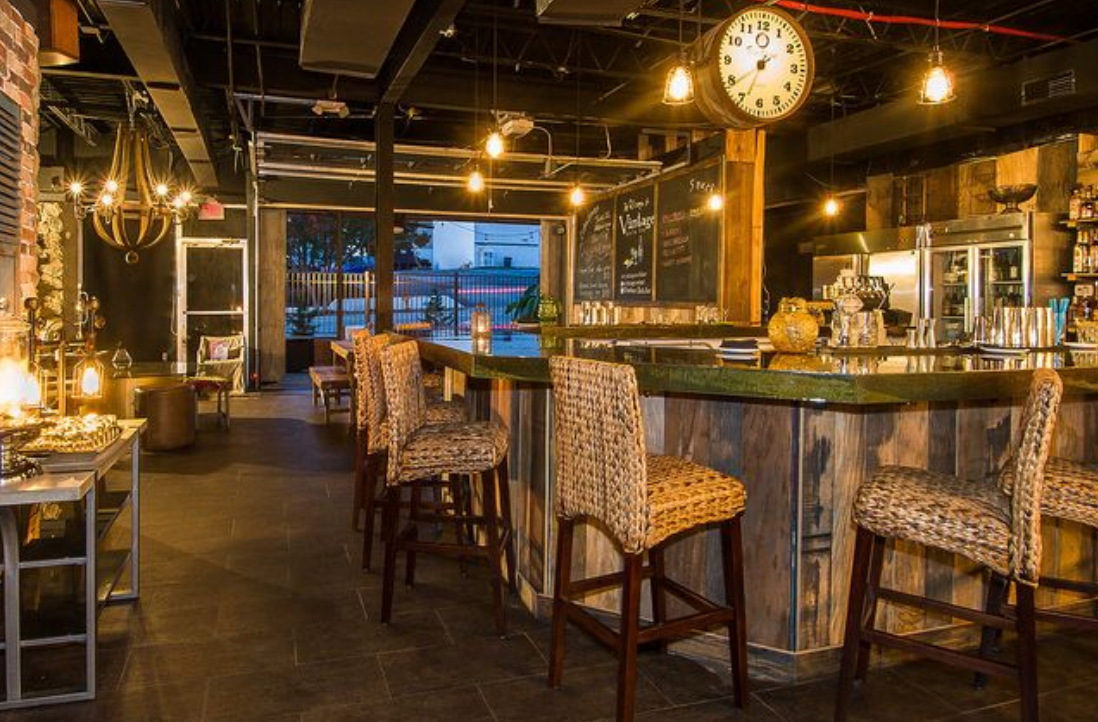 A bar with a clock hanging from the ceiling in a restaurant.
