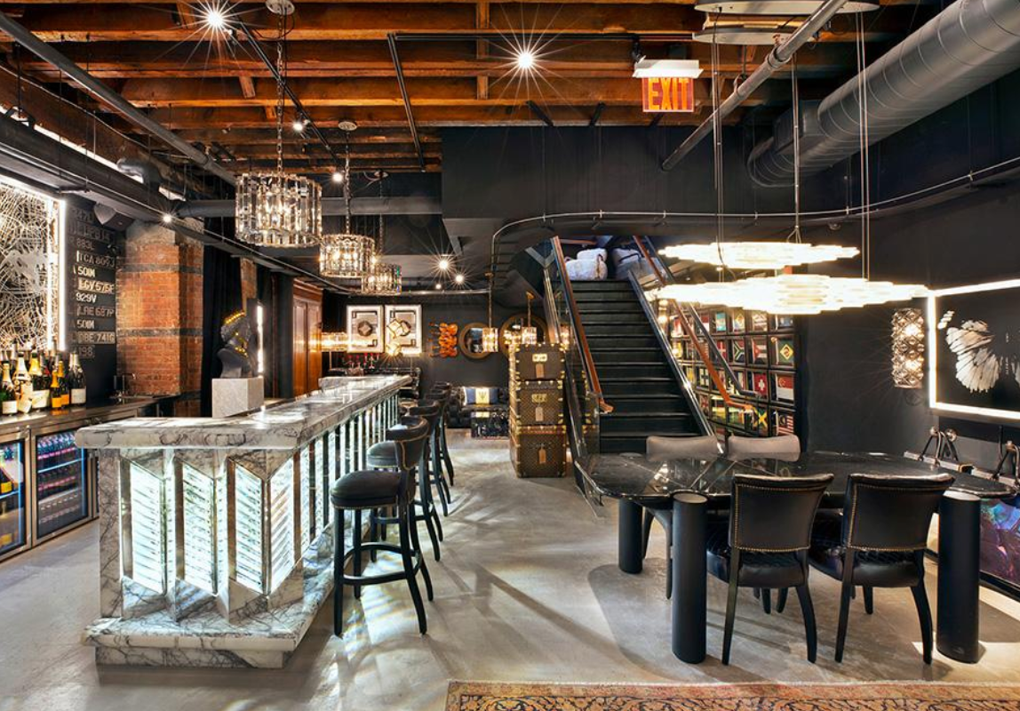 A large room with a bar , dining table , chairs and stairs.