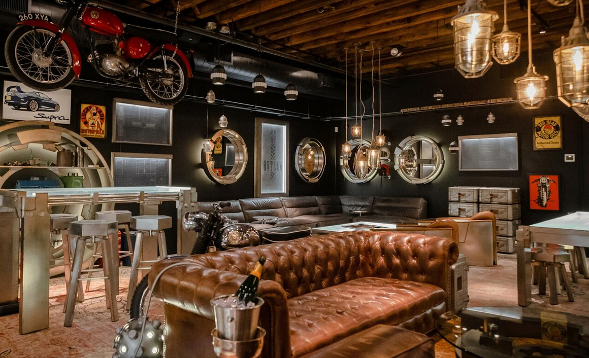 A living room with a couch , table , chairs and motorcycles hanging on the wall.