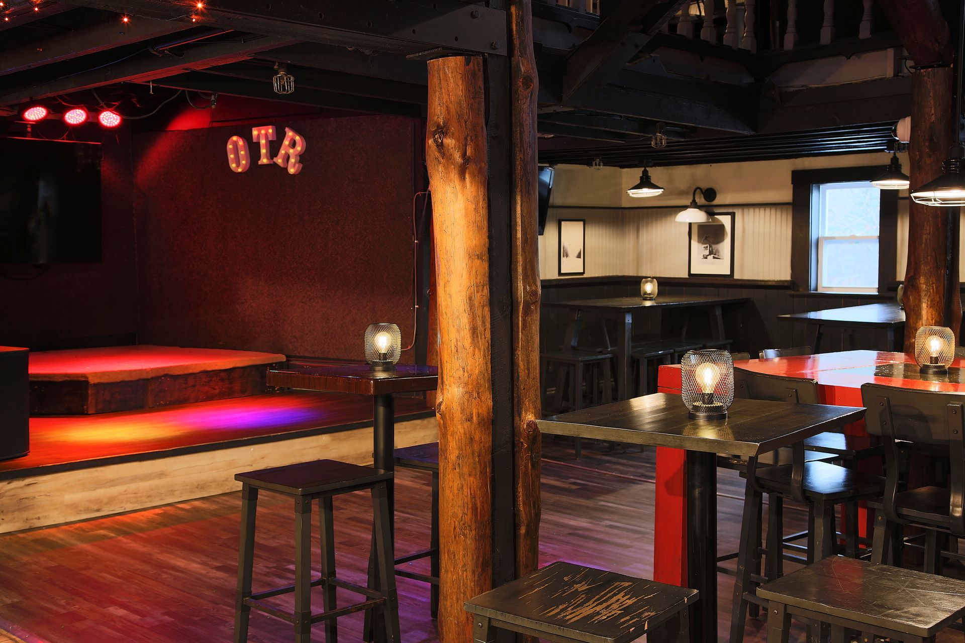 A room with tables and chairs and a stage with the word ota on it