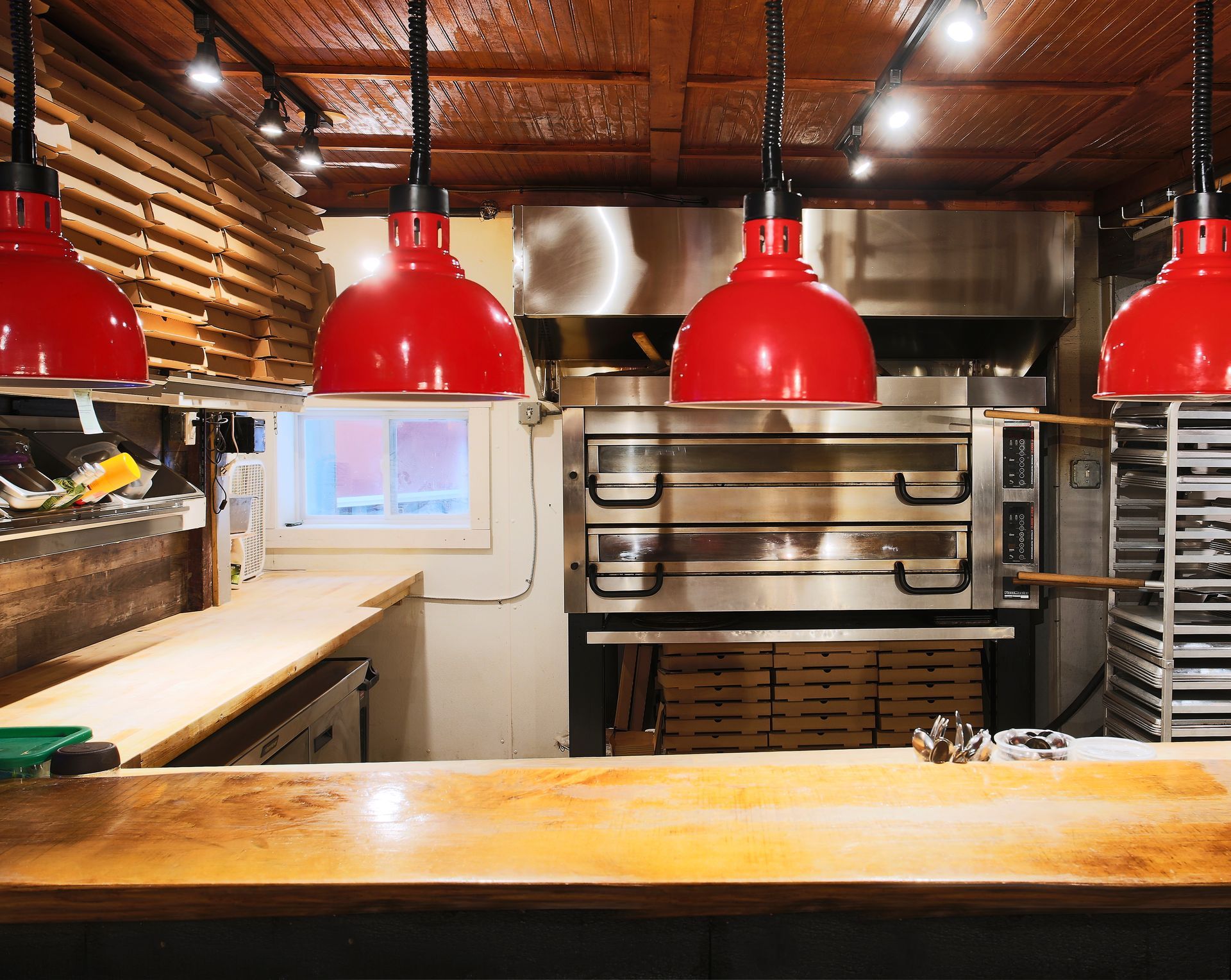 A kitchen with red lamps and a pizza oven