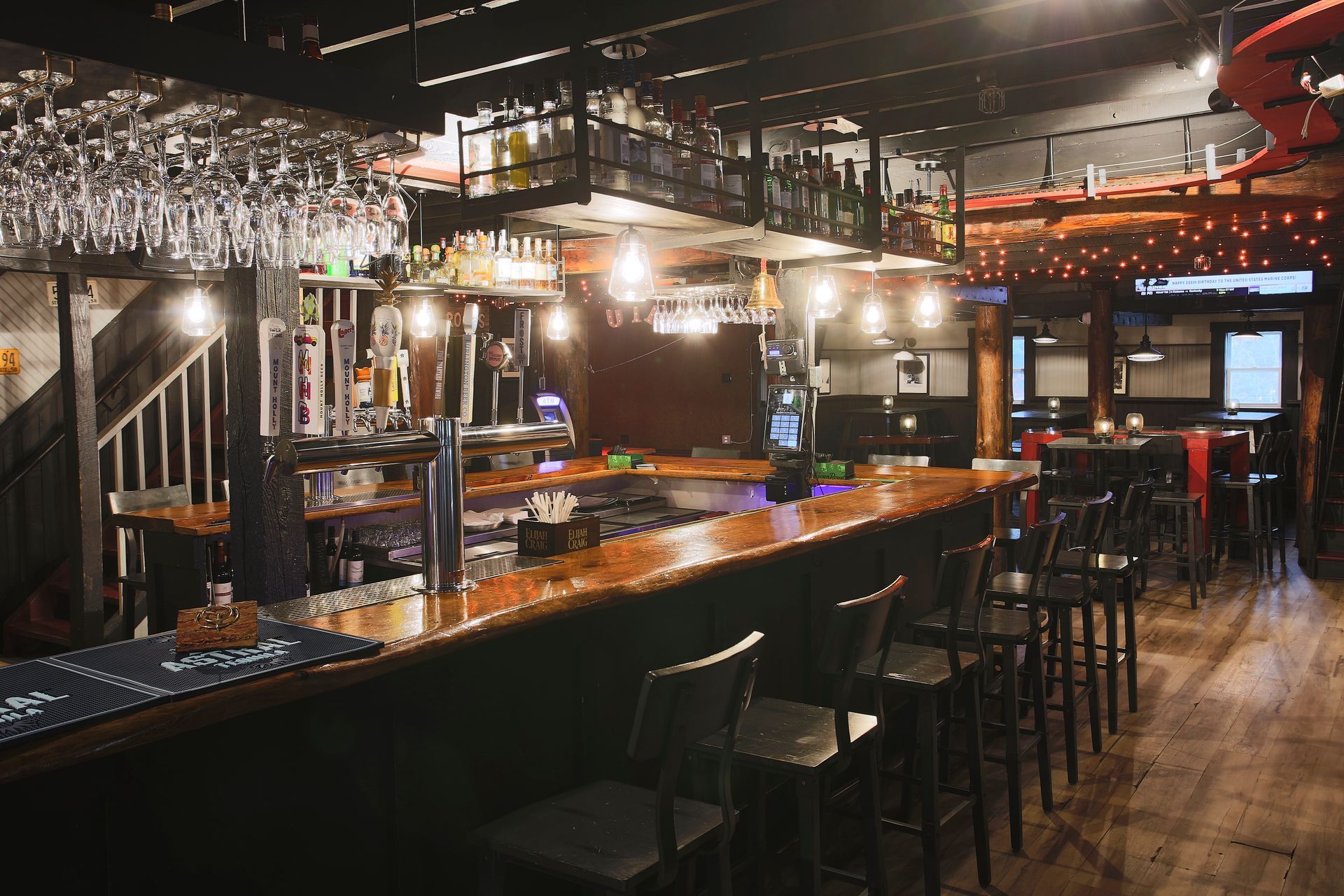 A bar with a lot of glasses hanging from the ceiling.