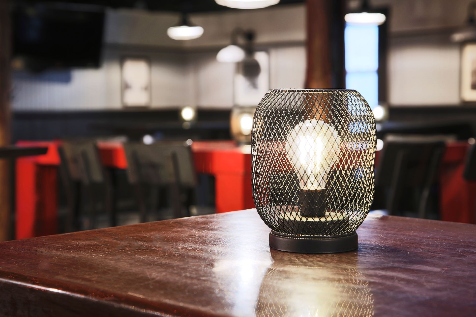 A lamp is sitting on a wooden table in a restaurant.