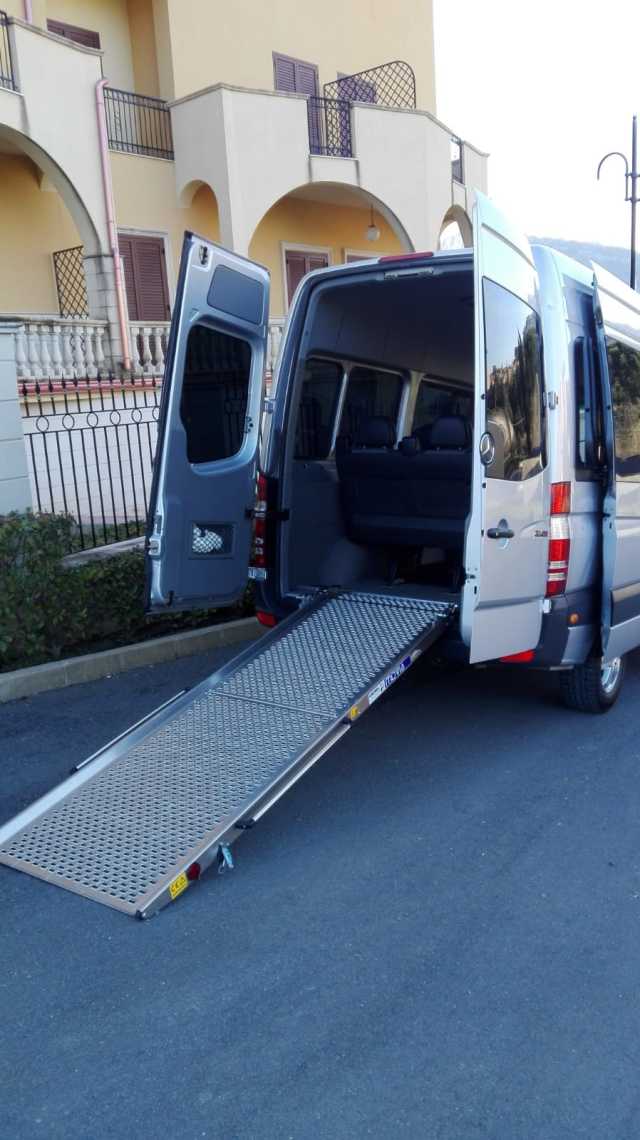 Un furgone con una rampa attaccata sul retro è parcheggiato sul ciglio della strada.