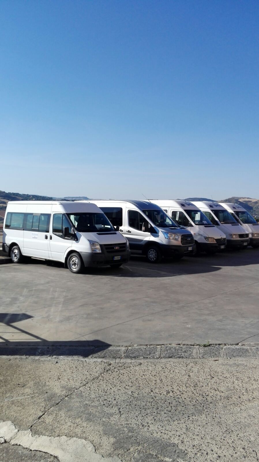 Una fila di furgoni bianchi sono parcheggiati in un parcheggio.