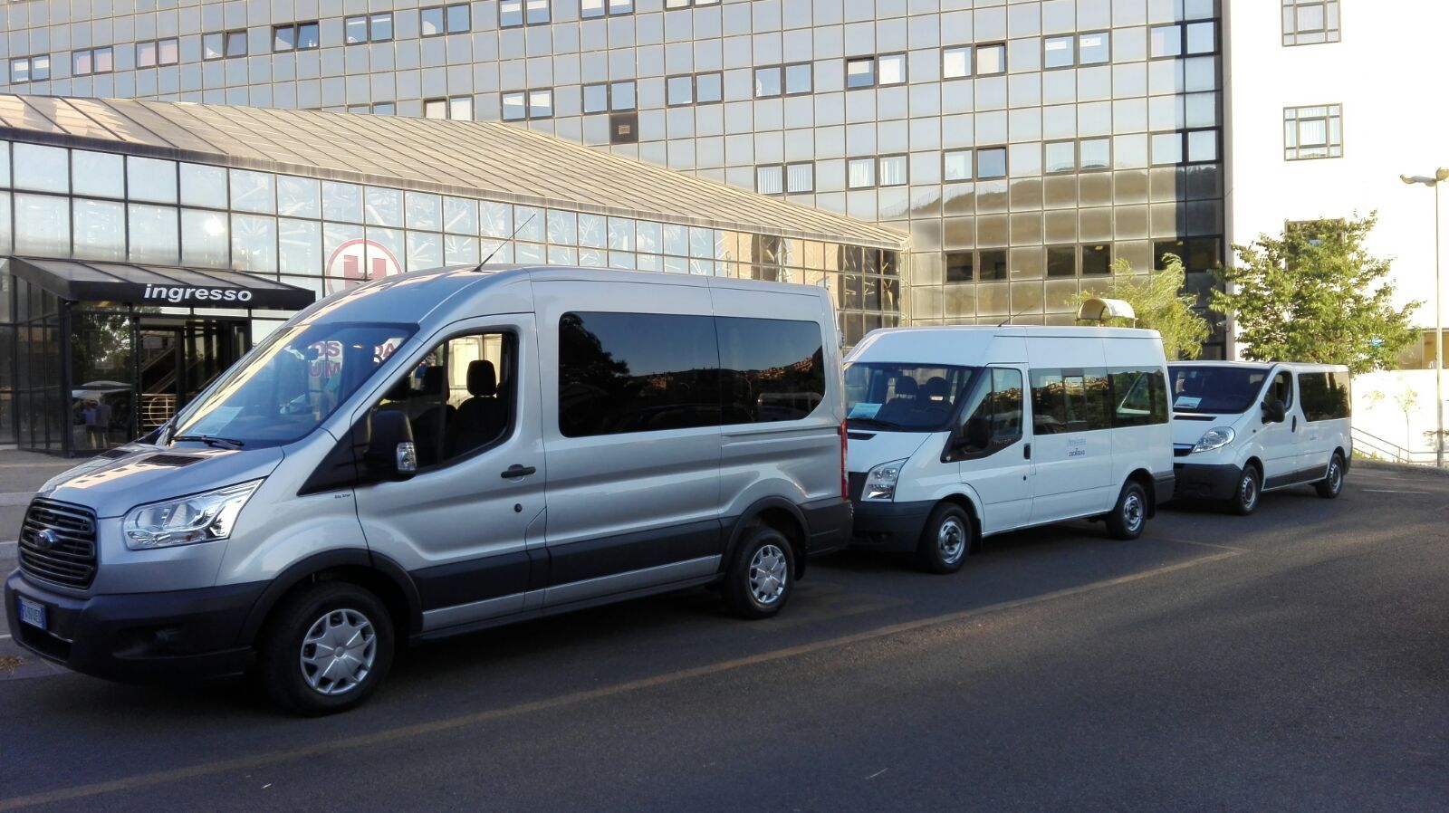 Una fila di furgoni è parcheggiata davanti a un edificio.