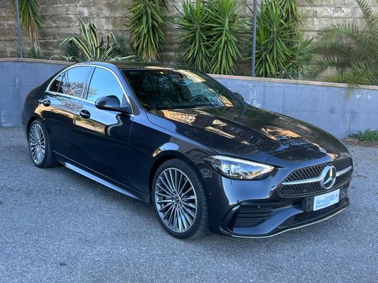 Una mercedes benz classe c nera è parcheggiata davanti a un muro.