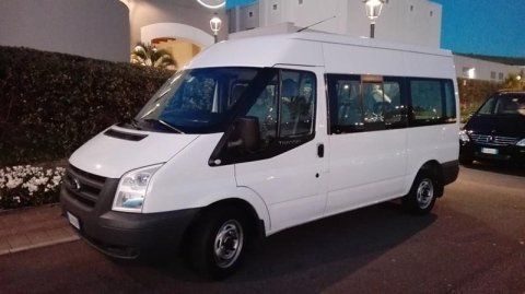 Un furgone bianco è parcheggiato in un parcheggio di fronte a un edificio.