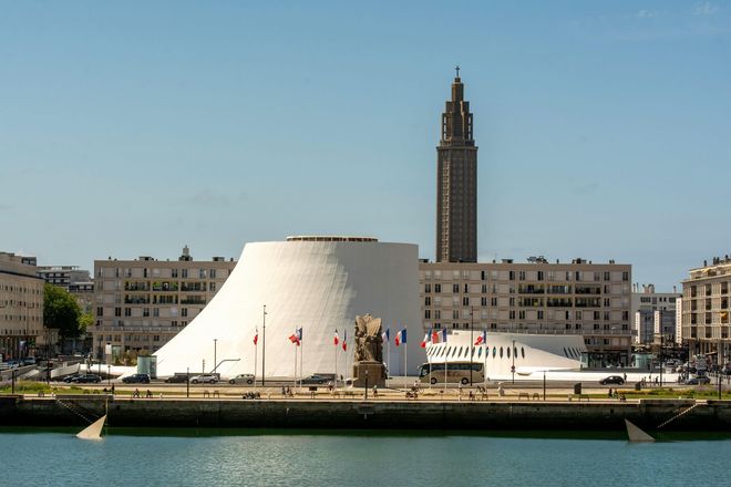Bâtiment blanc et cylindrique, haute tour, front de mer, Le Havre, France ; ciel bleu.