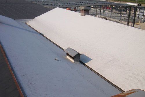 White corrugated metal roofs of industrial buildings with chimneys.