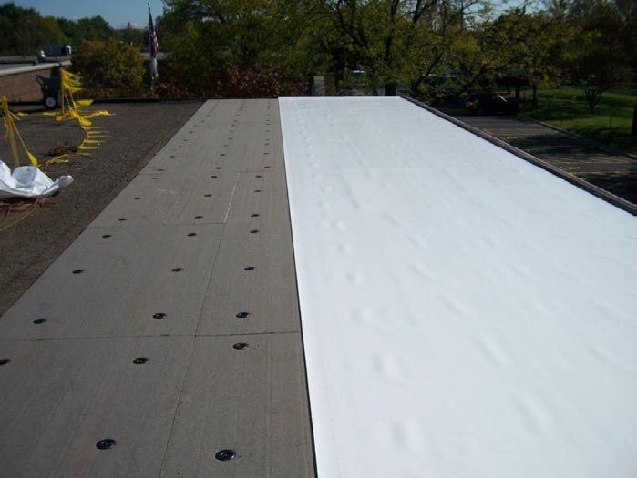 Flat roof partially covered with white membrane; the uncovered section is dark.