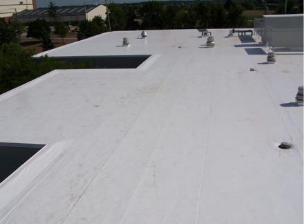 White commercial flat roof with vents and skylights.